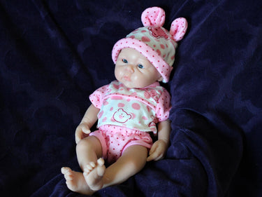 Realistic reborn baby doll dressed in pink bear-print outfit and matching hat, handmade newborn doll for collectors, play, or therapy